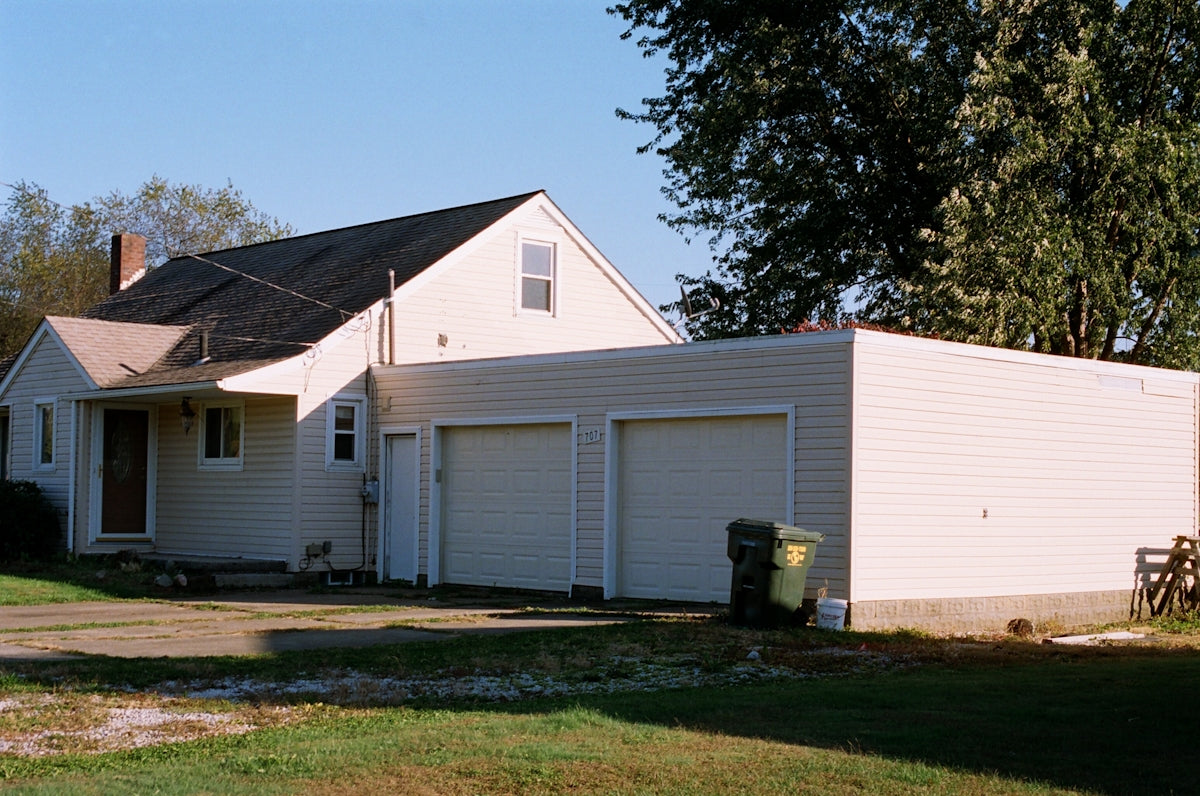 white and brown wooden house near green trees under blue sky during daytime